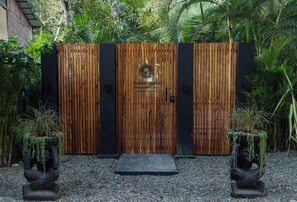 Una puerta de madera con un logotipo e información de contacto, flanqueada por dos estatuas a cada lado.