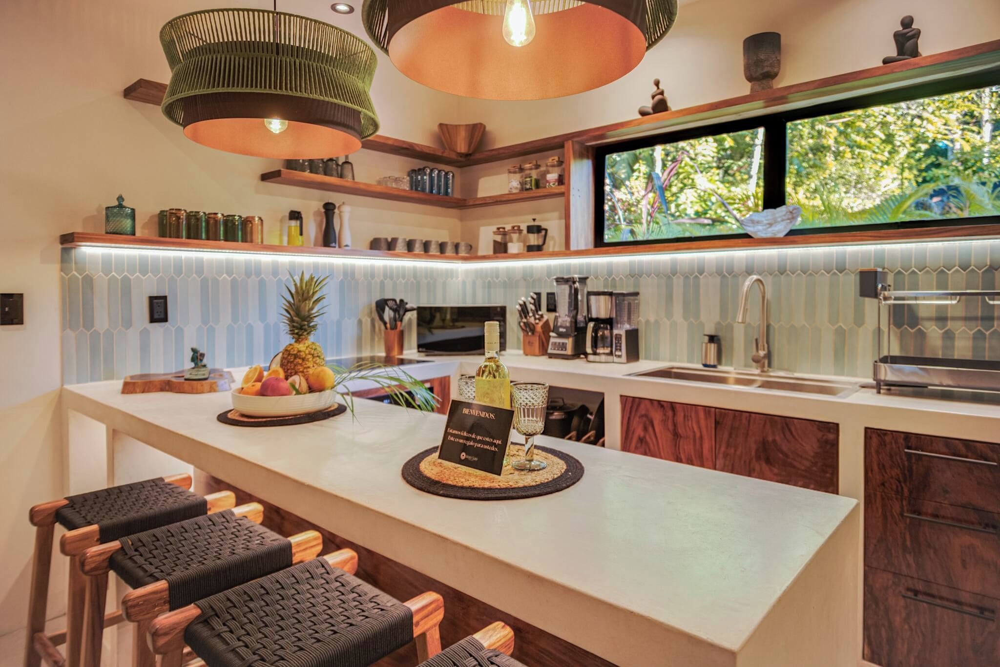 Una cocina moderna con una zona de bar, que cuenta con una isla grande con un frutero, una copa de vino y un cartel de bienvenida.