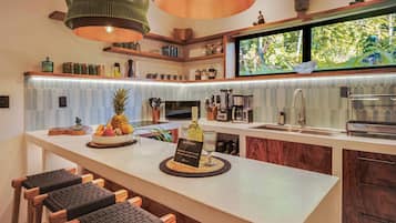 Una cocina moderna con una zona de bar, que cuenta con una isla grande con un frutero, una copa de vino y un cartel de bienvenida.