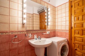 A bathroom with a sink, mirror, and washing machine. - Holiday Home in Nerja With Sea Views (Nerja)