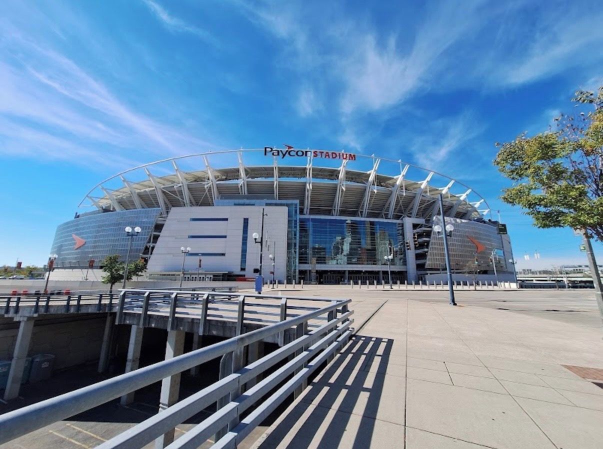 Paycor Stadium with a modern architectural design, featuring a large open entrance and a clear sky above.