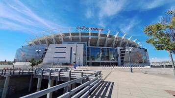 Paycor Stadium with a modern architectural design, featuring a large open entrance and a clear sky above.