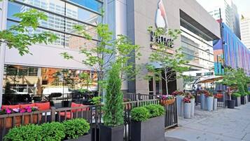 A modern building with a glass facade, outdoor seating, and potted plants.