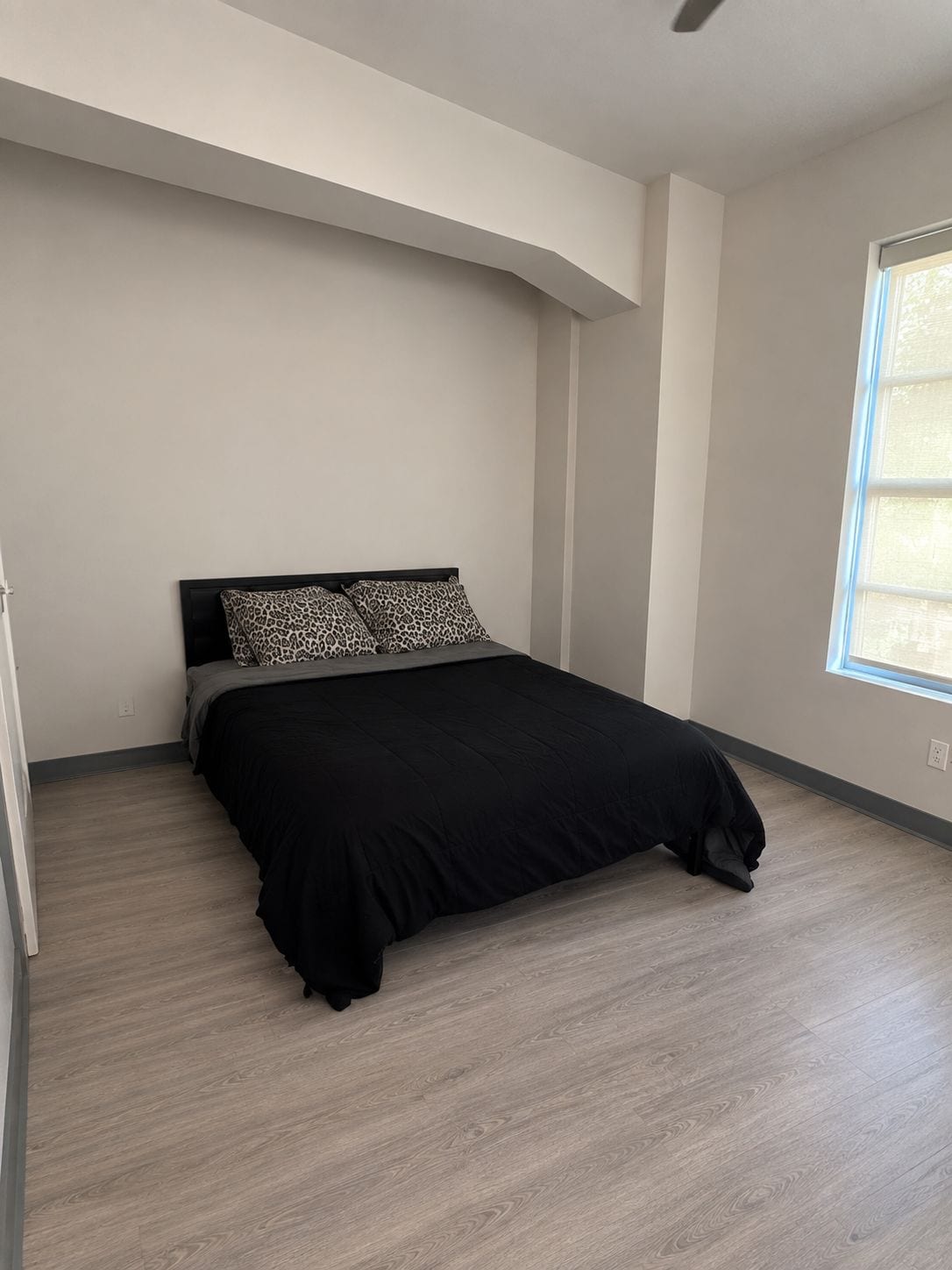 Quarto com cama, janela e ventilador de teto.