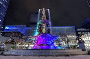 A nighttime view of a fountain with water jets and statues, surrounded by modern buildings. - Luxury Cincinnati Getaway Modern, Stylish & Spacious (Cincinnati)
