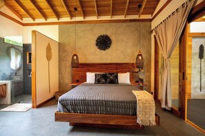 Um quarto espaçoso com cama grande, cabeceira de madeira e luminárias pendentes.