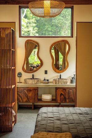 Une salle de bain avec deux lavabos en bois, un grand miroir et une fenêtre située au-dessus.