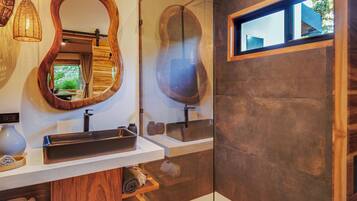 Un baño con tocador de madera, un espejo grande, ducha moderna y ventana con vistas.