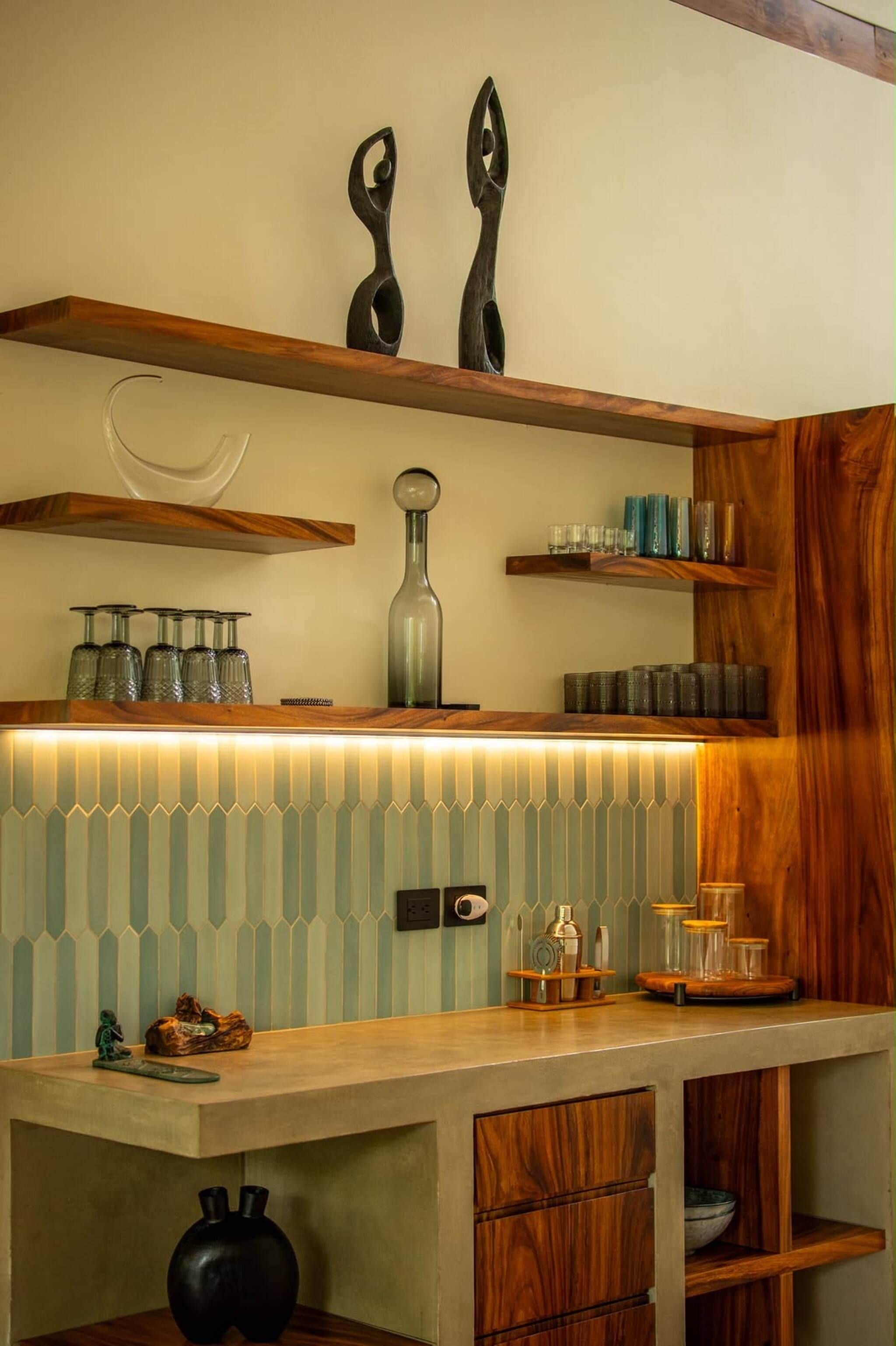 Una cocina con estantes de madera, salpicadero de azulejos y diversos utensilios de cocina.