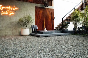 Una entrada moderna con puerta de madera, letrero de neón, un perro pequeño y una escalera.