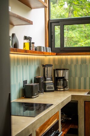 Una cocina moderna con estufa integrada, cafetera y licuadora sobre la encimera.