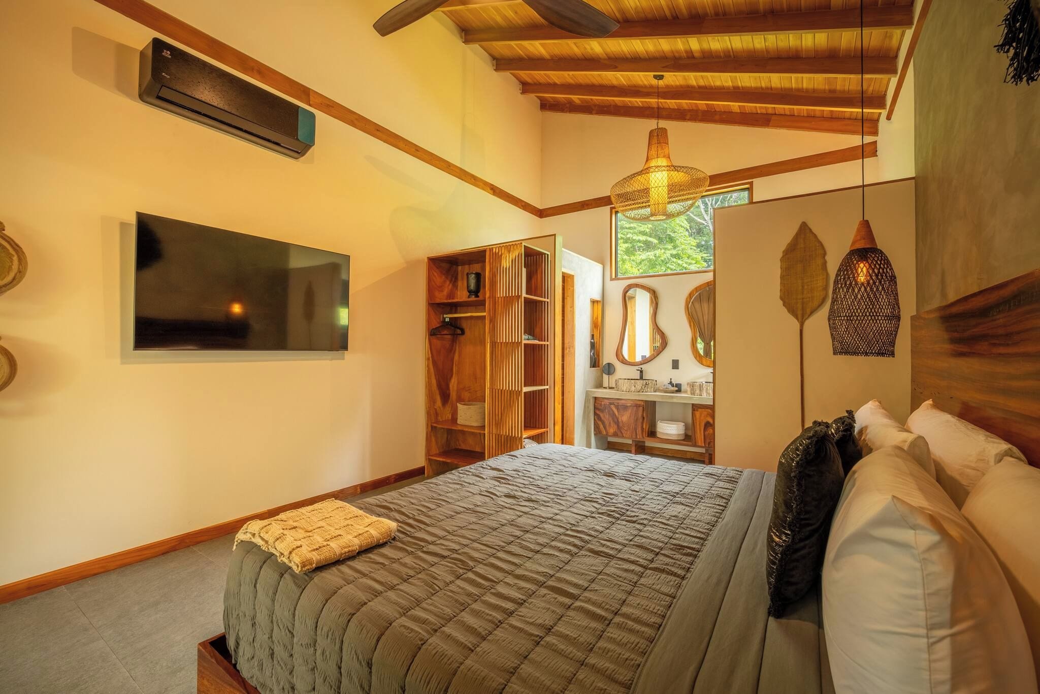 Un dormitorio con cama, armario, espejo y lámpara colgante.