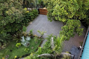 Un jardin avec un chemin de gravier, différentes plantes et une clôture en bois.