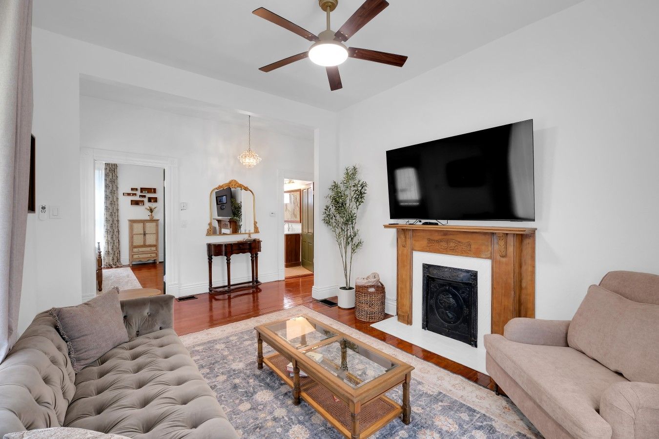 A living room with a fireplace, a television, and a ceiling fan.