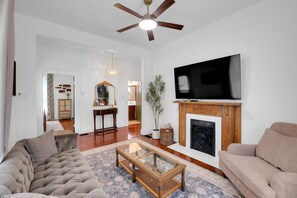 Una sala de estar con chimenea, televisor y ventilador de techo.