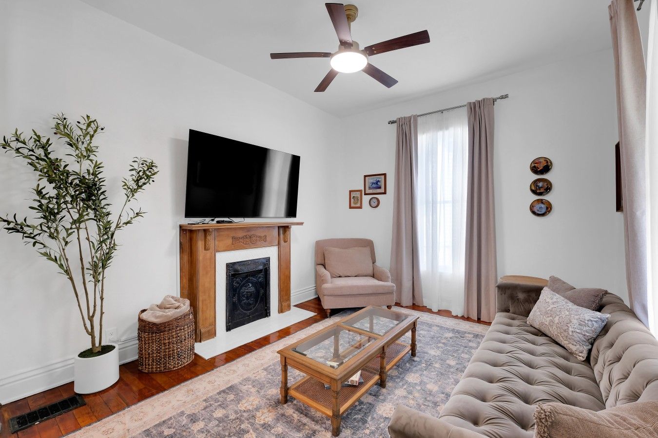 Ein Wohnzimmer mit Fernseher, Kamin, Sofa und Deckenventilator.
