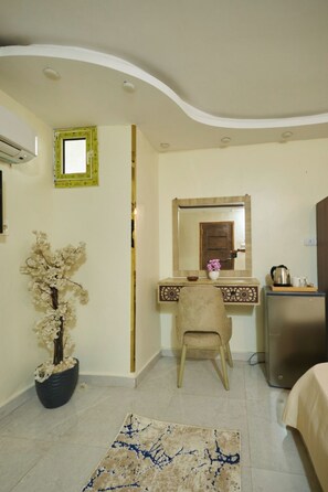 Una habitación con escritorio, silla, cama y planta en maceta.