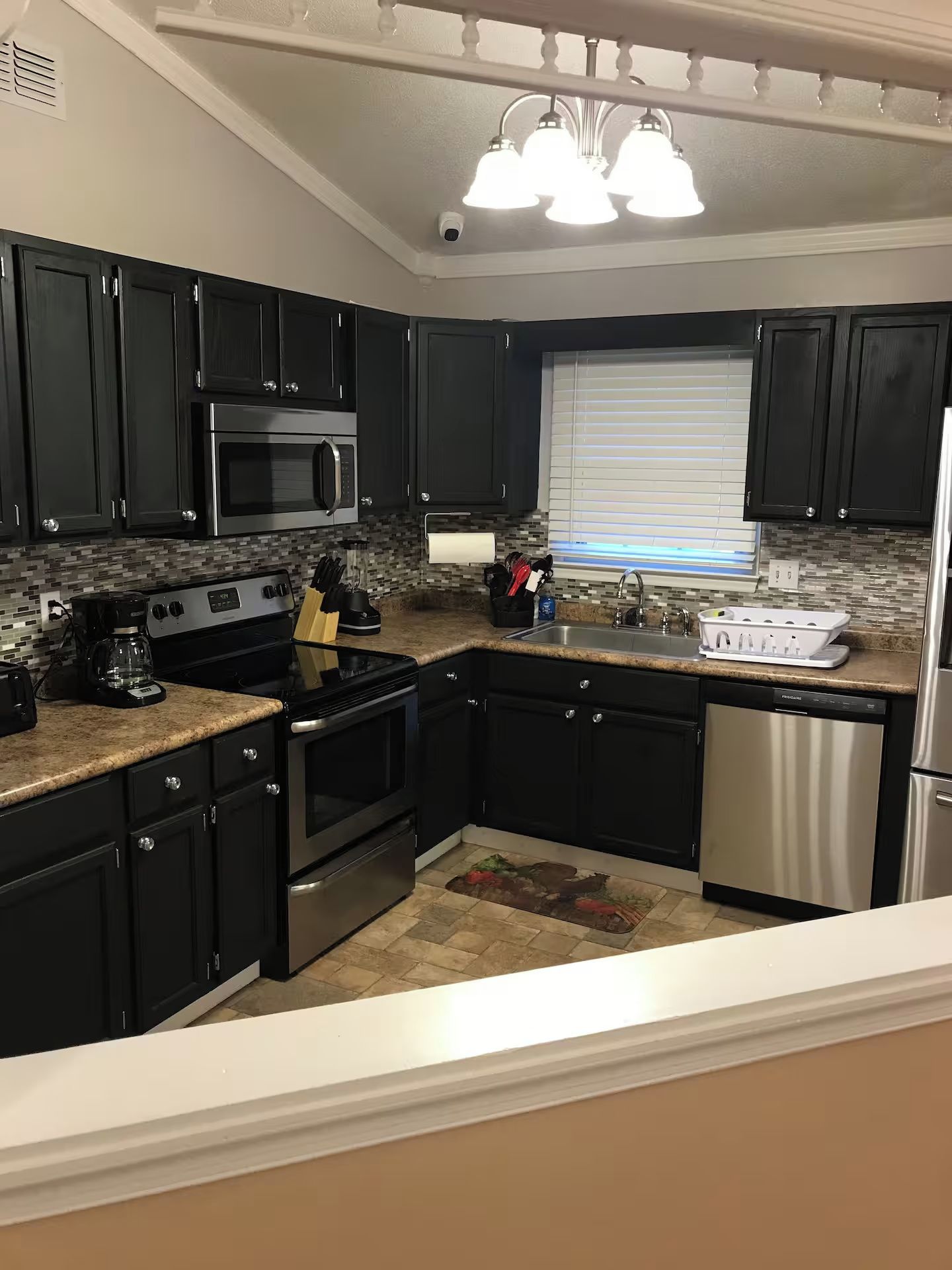 A modern kitchen with black cabinets, stainless steel appliances, a built-in oven, and a dishwasher.