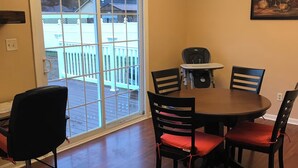 Uma sala de jantar com mesa, cadeiras, uma janela com vista e um candelabro.