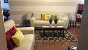 Uma sala de estar com dois sofás, uma mesa de centro e um relógio na parede.
