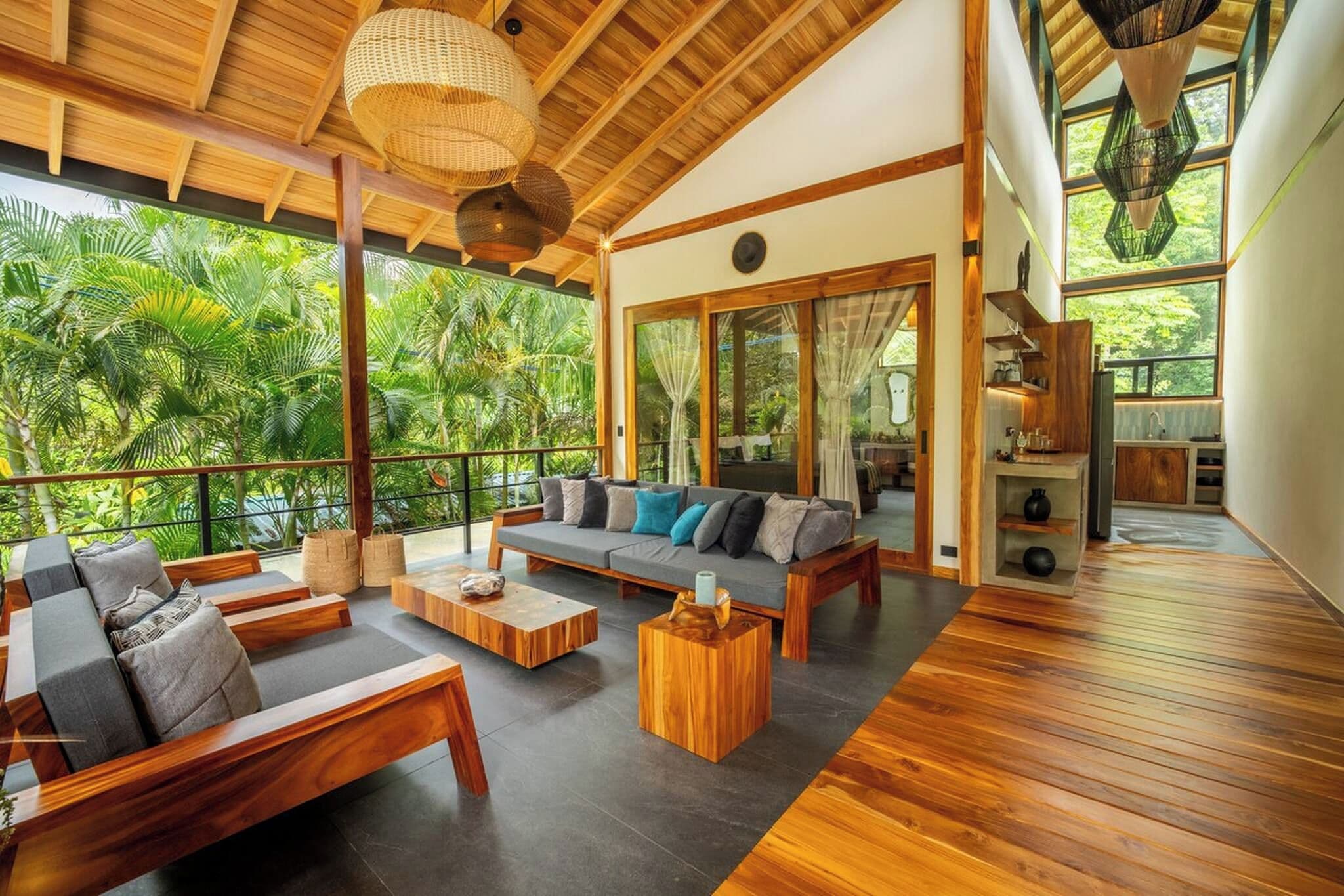 Amplia sala de estar con techo de madera, un conjunto de sofás y vistas a exuberante vegetación.