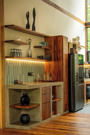 Eine moderne Küche mit Holzschränken, einem integrierten Weinschränkchen und einem großen Kühlschrank.