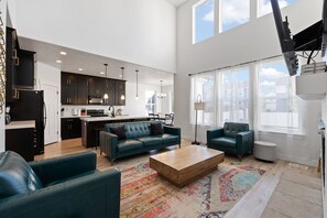 A spacious living area with a sofa, coffee table, and a view of the kitchen and dining area. - Spacious 6-bedroom house in lovely American Fork with AC (American Fork)