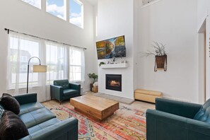 Ein modernes Wohnzimmer mit Kamin, großem Fernseher und bequemen Sitzmöglichkeiten.