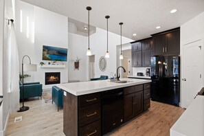 A modern kitchen with a central island, dark cabinetry, and a built-in refrigerator. - Spacious 6-bedroom house in lovely American Fork with AC (American Fork)