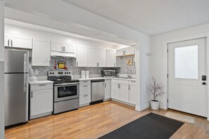 A modern kitchen with white cabinets, stainless steel appliances, and a wooden floor. - Spacious 6-bedroom house in lovely American Fork with AC (American Fork)