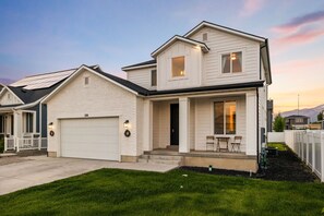 A two-story house with a garage, a front porch with chairs, and a well-maintained lawn. - Spacious 6-bedroom house in lovely American Fork with AC (American Fork)