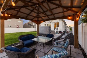 An outdoor patio with a covered seating area, a table, and a covered play structure. - Spacious 6-bedroom house in lovely American Fork with AC (American Fork)