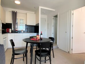 A modern kitchen with a dining table, chairs, and a bottle of wine. - Apartment in Nerja With Sea Views & Pools (Nerja)