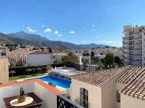 A residential area with a swimming pool, a mountain in the background, and a clear sky. - Apartment in Nerja With Sea Views & Pools (Nerja)