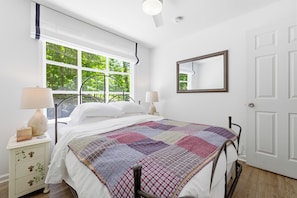 A bedroom with a bed, a nightstand, a window, a mirror, and a door. - Cozy 2-BR Shenandoah Cottage, Pet Friendly (Shenandoah)