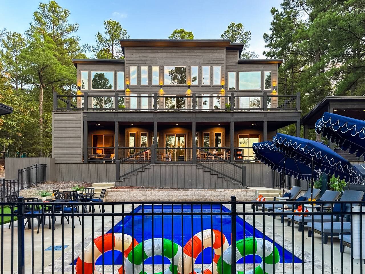 Ein modernes, zweistöckiges Gebäude mit überdachter Außenbereich-Sitzgelegenheit und einem Pool mit farbenfrohem Design.