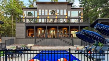 Ein modernes, zweistöckiges Gebäude mit überdachter Außenbereich-Sitzgelegenheit und einem Pool mit farbenfrohem Design.