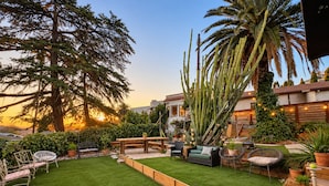 A well-maintained backyard with a grassy lawn, wooden deck, and various seating arrangements. - 
The Perch  2BR Eagle Rock Home + Views near DTLA (Los Angeles)