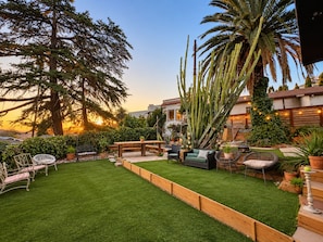 A well-maintained backyard with a grassy lawn, wooden deck, and various seating arrangements. - 
The Perch  2BR Eagle Rock Home + Views near DTLA (Los Angeles)