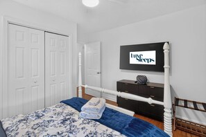 Ein Schlafzimmer mit einem Bett, einem Schminktisch, einem Fernseher und einer Tür.