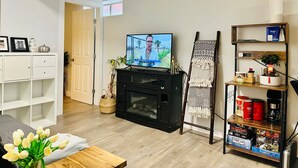 A living room with a television, a fireplace, a bookshelf, and a door leading to another room. - Location! Close to Everything! FREE Banff Pass! (Calgary)