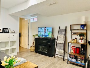 Ein Wohnzimmer mit Fernseher, Kamin, Bücherregal und einer Tür zu einem anderen Raum.