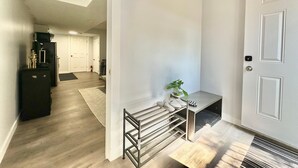 A hallway with a black metal rack, a small table with a plant, and a white door. - Location! Close to Everything! FREE Banff Pass! (Calgary)