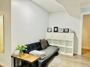 A modern living room with a black sofa, a wooden coffee table, a white cabinet, and a vase of white flowers.
