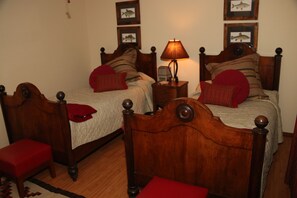 A bedroom with two wooden beds, a nightstand, a lamp, and framed pictures on the wall. - Best View on the Little Red River, Plus walk-in river access (Heber Springs)