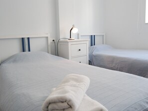 A hotel room with two beds, a nightstand with a lamp, and a window. - Apartment in Nerja Near Carabeillo Beach (Nerja)