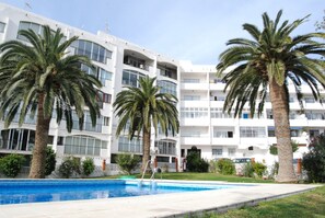 A modern building with a pool, palm trees, and a clear sky. - Apartment in Nerja Near Carabeillo Beach (Nerja)