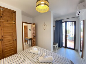 A hotel room with a bed, a wardrobe, a desk, and a view of the outside. - Apartment in Nerja With Coastal Views & Pool (Nerja)