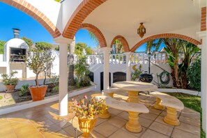 An outdoor patio with a barbecue grill, a round table, and potted plants. - Apartment in Nerja Near the Beach (Nerja)