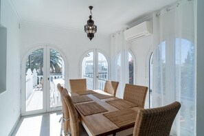 A dining area with a large table, wicker chairs, and a hanging lantern. - Apartment in Nerja Near the Beach (Nerja)